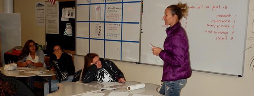 Photograph of a teacher instructing children in a classroom.