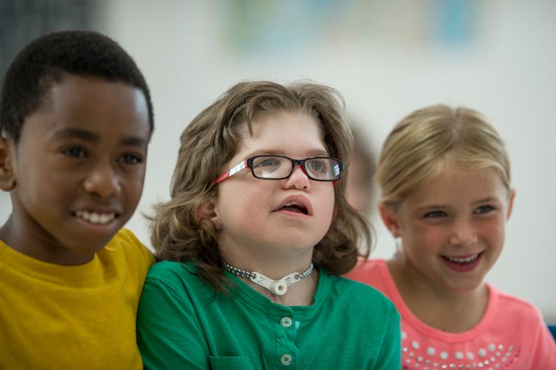 Image of three young children sitting together smiling.