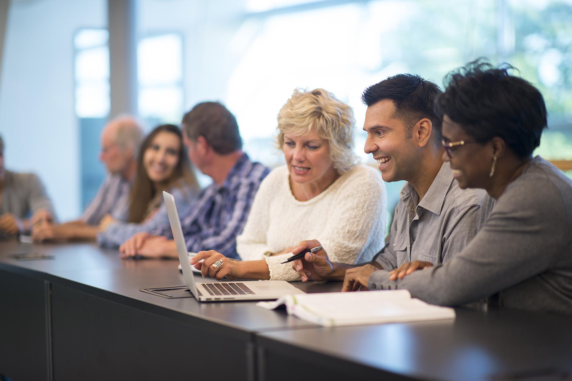 Group of diverse people in a meeting looking at computer