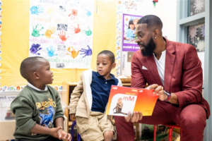 Dr. Rashad Anderson exchanging a handshake with a young female student in an elementary school cafeteria.