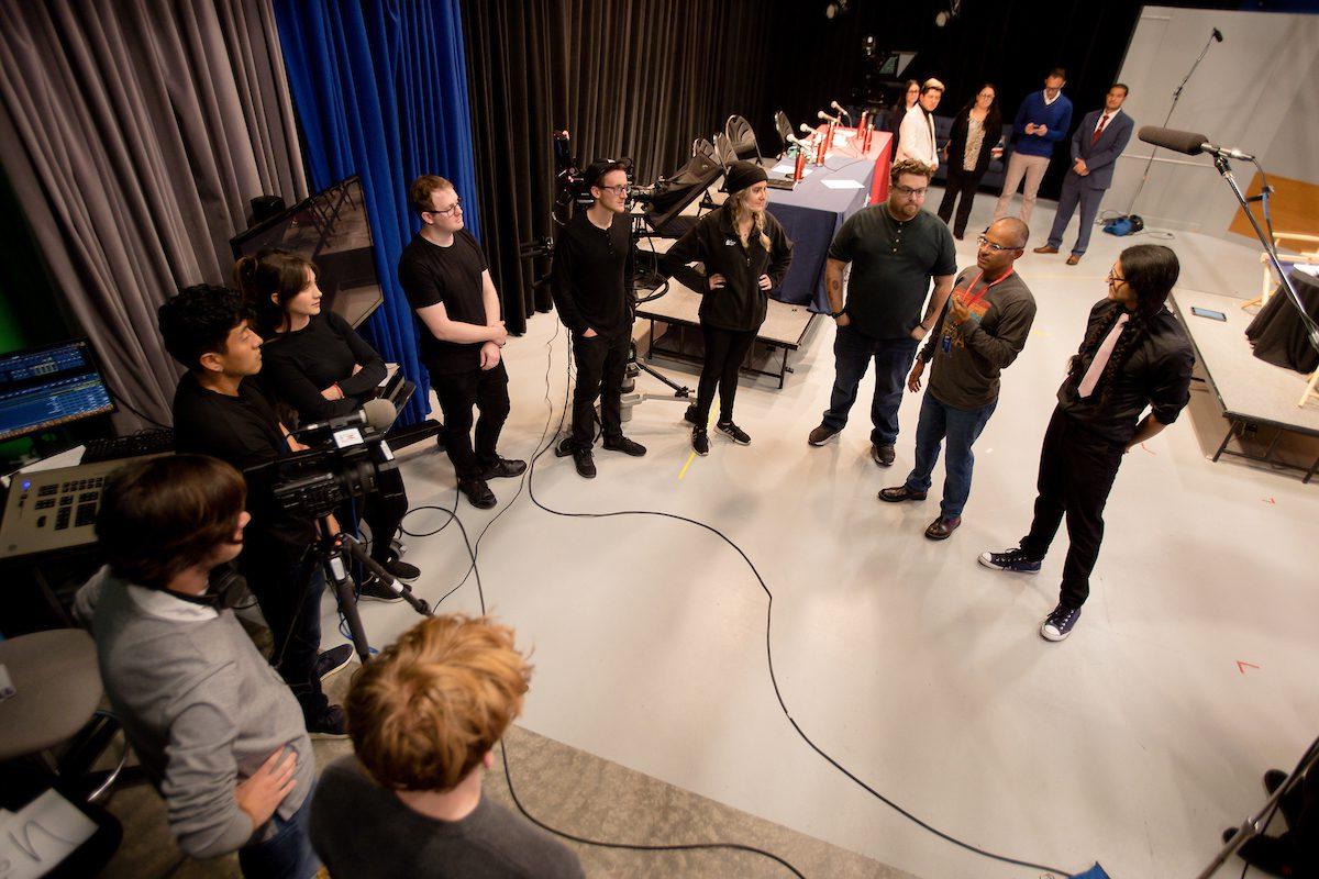 Assistant Professor, Alfredo Sanchez, congratulates and talks with journalism students after a successful taping.